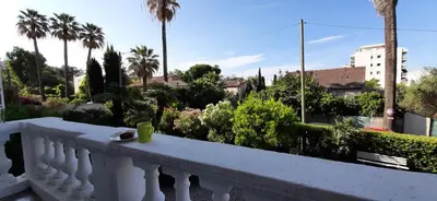 a balcony with a white railing and trees and bushes at Winter Palace in Cannes