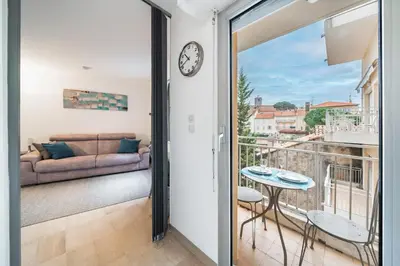 a room with a balcony with a couch and a clock at Studio au calme dans le quartier du Suquet - Proche Croisette et centre-ville in Cannes