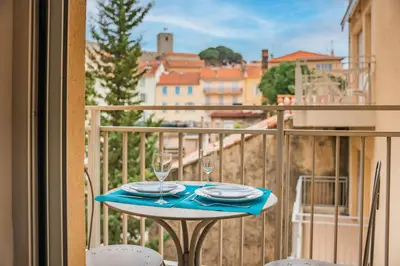 a table with plates and glasses on a balcony at Studio au calme dans le quartier du Suquet - Proche Croisette et centre-ville in Cannes