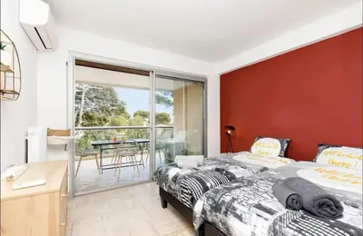 two beds in a bedroom with a red wall at Appartement spacieux avec vue au Cannet 114 m² in Le Cannet