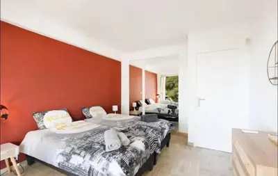 a bedroom with a bed with a red wall at Appartement spacieux avec vue au Cannet 114 m² in Le Cannet