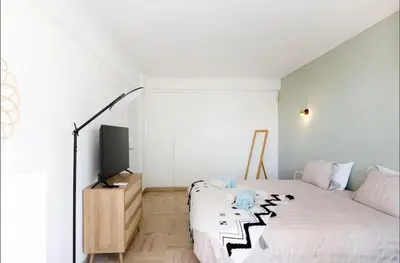 a white bedroom with a bed and a television at Appartement spacieux avec vue au Cannet 114 m² in Le Cannet