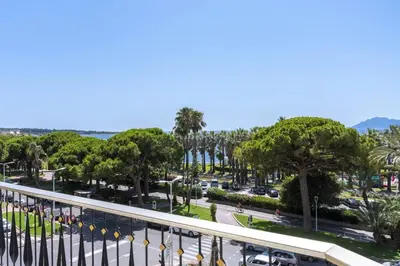 a view from a balcony of a street with palm trees at REF 2012 - Cannes Croisette - Apartment to rent sea view in Cannes
