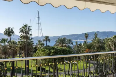 a balcony with a view of the ocean and palm trees at REF 2012 - Cannes Croisette - Apartment to rent sea view in Cannes