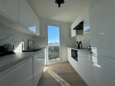a kitchen with white counters and a large window at Les Venitiennes in Cannes