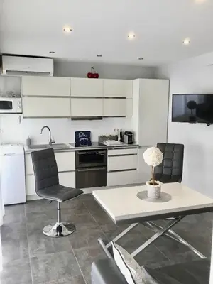 a kitchen with white cabinets and a table and chairs at Elegant F2 with all comforts in center of Cannes in Cannes