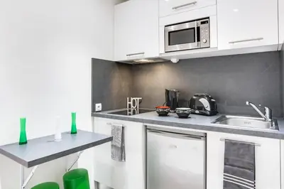 a kitchen with white cabinets and a microwave at Cannes centre Cosy appartement avec mezzanine in Cannes