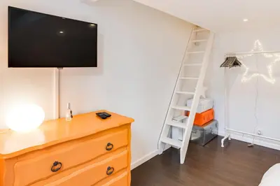 a bedroom with a dresser with a television on a wall at Cannes centre Cosy appartement avec mezzanine in Cannes