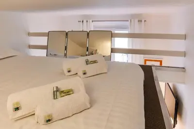a bedroom with a white bed with pillows and a mirror at Cannes centre Cosy appartement avec mezzanine in Cannes
