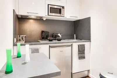 a kitchen with white cabinets and a microwave at Cannes centre Cosy appartement avec mezzanine in Cannes