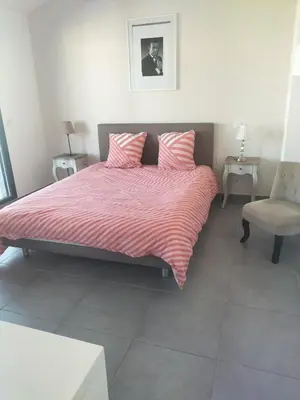 a bedroom with a bed with pink sheets and a chair at suite unique in Cannes