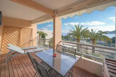 a balcony with a glass table and chairs and palm trees at Auré-Parking-Piscine-Terrasse-VCA in Cannes