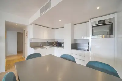 a kitchen with white cabinets and a table and chairs at Auré-Parking-Piscine-Terrasse-VCA in Cannes