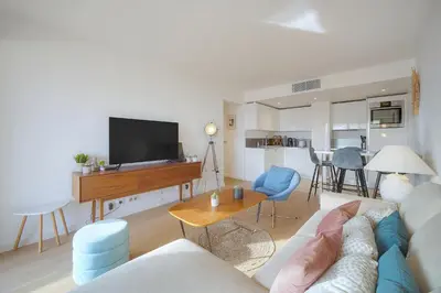 a living room with a couch and a tv and a table at Auré-Parking-Piscine-Terrasse-VCA in Cannes