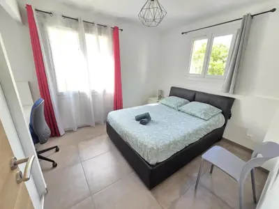 a bedroom with a bed and a chair and windows at Superbe Appartement Familial in Cannes