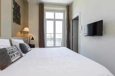 a bedroom with a large white bed with a flat screen tv at Florella Jean Jaures Apartment in Cannes