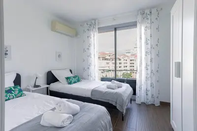 two beds in a room with a window at Diplomate - 2 chambres, 15mn du Palais, charmant, balcon, clim in Cannes