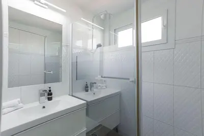 a white bathroom with a sink and a mirror at Diplomate - 2 chambres, 15mn du Palais, charmant, balcon, clim in Cannes