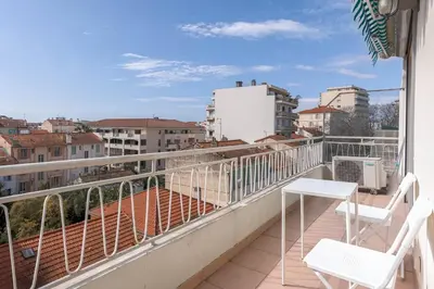 a balcony with two chairs and a view of a city at Diplomate - 2 chambres, 15mn du Palais, charmant, balcon, clim in Cannes