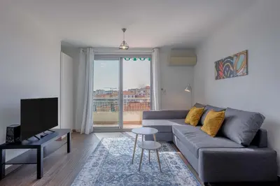 a living room with a gray couch and a tv at Diplomate - 2 chambres, 15mn du Palais, charmant, balcon, clim in Cannes