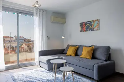 a living room with a couch and a large window at Diplomate - 2 chambres, 15mn du Palais, charmant, balcon, clim in Cannes