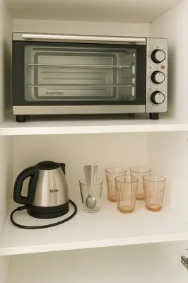 a toaster oven on a shelf with some glasses at Studio chic à 200 m du Palais des Festivals, au cœur du shopping Cannois in Cannes