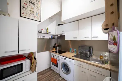 a kitchen with white cabinets and a washing machine at Les voiles des Régates, à 5 minutes du centre à pied, 15 minutes de la mer in Cannes