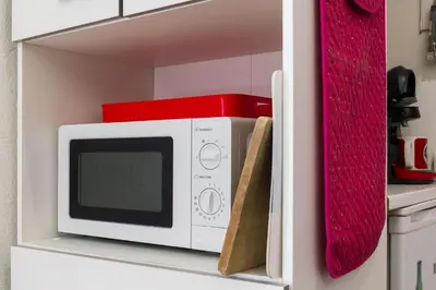a white microwave on a shelf in a kitchen at Les voiles des Régates, à 5 minutes du centre à pied, 15 minutes de la mer in Cannes