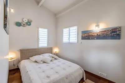 a white bedroom with a bed and two windows at Diane By Terrys Homes in Cannes
