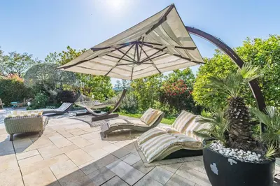 a patio with lounge chairs and an umbrella at Diane By Terrys Homes in Cannes