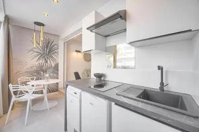 a kitchen with white cabinets and a sink and a table at Palace - Ultra center - 2 min sea - VCA in Cannes