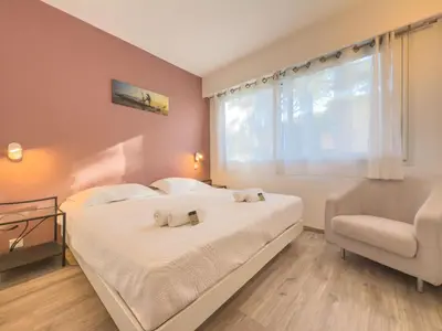 a bedroom with two beds and a chair and a window at Le Cozy by Winsome Destination in Cannes