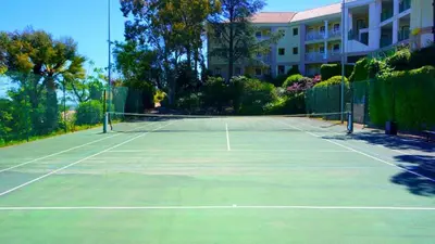 a tennis court in front of a building at Vue mer imprenable, piscine à débordement - Cannes in Cannes