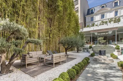a garden with benches and trees in front of a building at Heart of Cannes Luxury Stay - Steps from Beach & Palais in Cannes