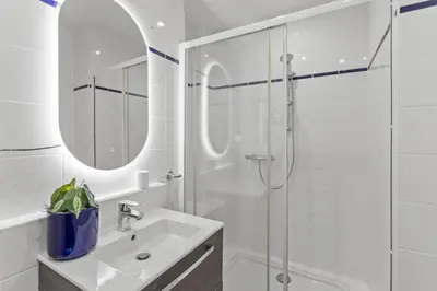 a white bathroom with a sink and a shower at Appartement à Cannes in Cannes