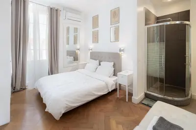 a white bedroom with a bed and a glass shower at Center of Cannes 100m2 bright apartment in Cannes