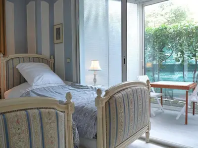 a bedroom with a bed and a table and a window at Appartement jardin in Cannes