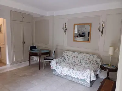 a bedroom with a bed and a table and a mirror at Appartement jardin in Cannes
