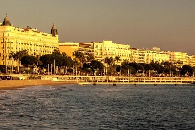 a large building on the beach next to the water at Family Sea view with pools near shops and beaches in Cannes