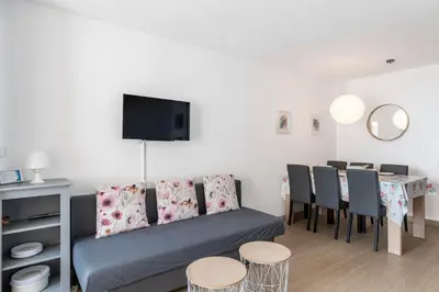 a living room with a couch and a table with chairs at Family Sea view with pools near shops and beaches in Cannes