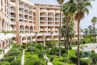 an exterior view of the resort with palm trees at Family Sea view with pools near shops and beaches in Cannes