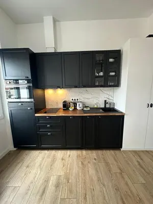 a kitchen with black cabinets and a wooden floor at Studio cosy, 8 min à pied du Palais et de la Plage in Cannes