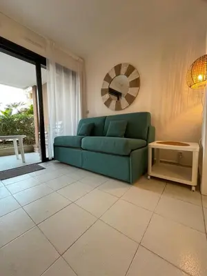 a living room with a green couch and a mirror at Appartement Cannes, Piscine - Terasse - 4 Personnes in Cannes