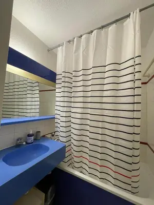 a bathroom with a shower curtain and a blue sink at Appartement Cannes, Piscine - Terasse - 4 Personnes in Cannes