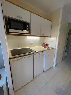 a small kitchen with white cabinets and a microwave at Appartement Cannes, Piscine - Terasse - 4 Personnes in Cannes