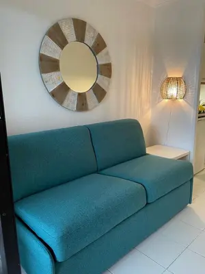 a blue couch in a living room with a mirror at Appartement Cannes, Piscine - Terasse - 4 Personnes in Cannes