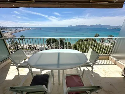 a table and chairs on a balcony with the ocean at Beachfront 2-bedroom apartment with balcony in Cannes