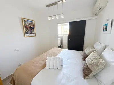 a white bedroom with a large bed with two pillows at Beachfront 2-bedroom apartment with balcony in Cannes