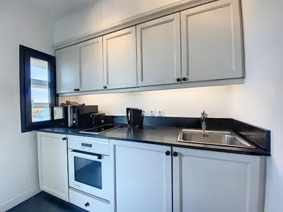 a kitchen with white cabinets and a sink at 1-bedroom beachfront apartment with sea view in Cannes