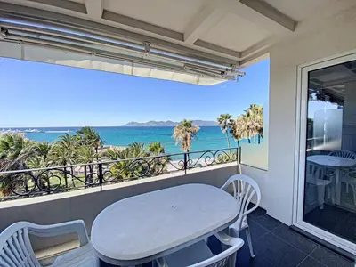 a balcony with a table and a view of the ocean at 1-bedroom beachfront apartment with sea view in Cannes